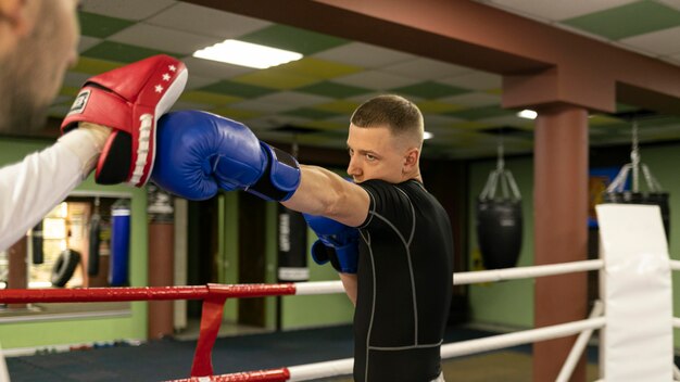 Vue latérale du boxeur masculin avec des gants exercice avec formateur