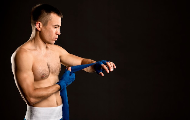 Vue latérale du boxeur masculin mettant sur la protection des mains avec copie espace