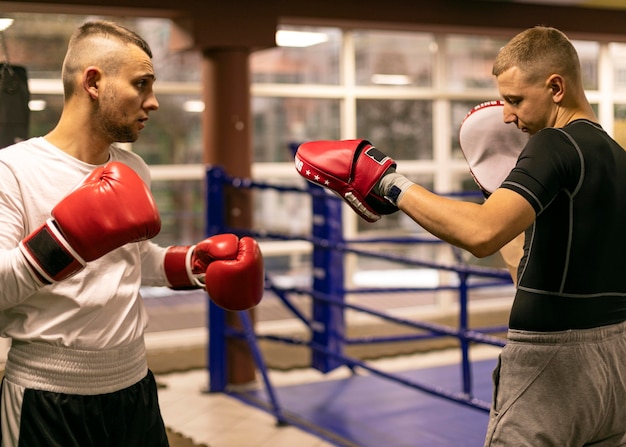 Vue latérale du boxeur masculin pratiquant avec formateur