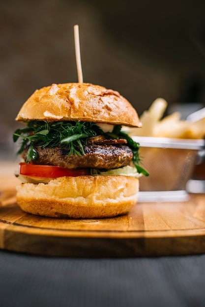 Vue latérale du burger avec escalope de viande sur une planche de bois