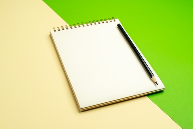 Vue latérale du cahier blanc avec stylo sur fond blanc et jaune