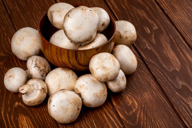 Vue latérale du champignon aux champignons frais dans un bol sur fond rustique en bois