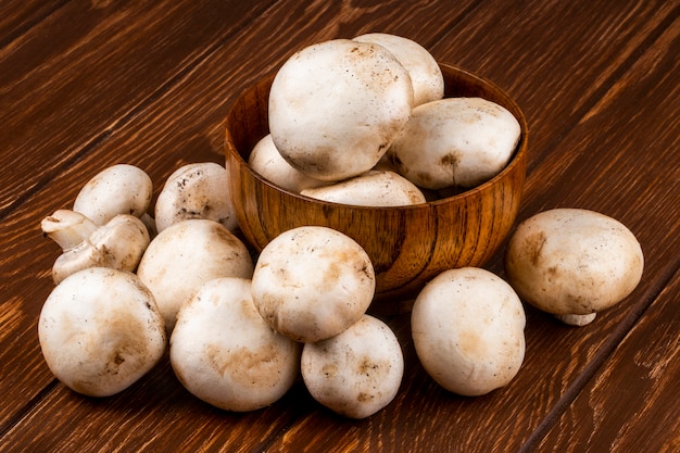 Vue latérale du champignon aux champignons frais dans un bol sur fond rustique en bois