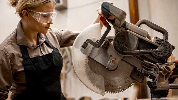 Photo gratuite vue latérale du charpentier féminin avec outil et lunettes