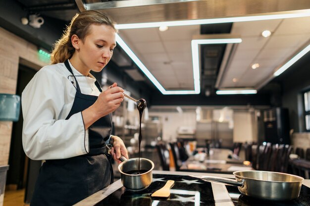 Vue latérale du chef féminin faisant la sauce