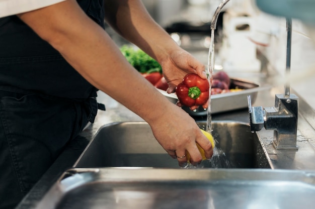 Vue latérale du chef masculin lave les légumes