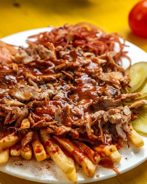 Vue latérale du chiken doner kebab sur la plaque avec du pain frites tomates cornichons et sauce à l'oignon