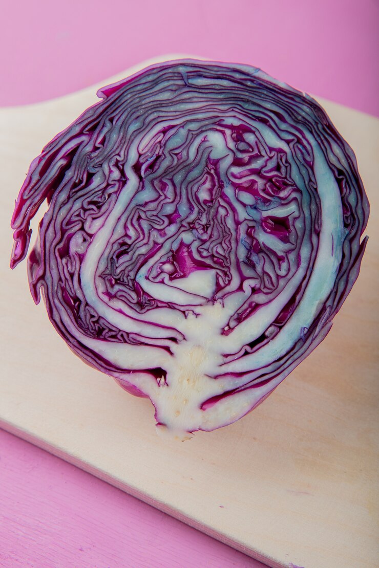 Photo gratuit vue latérale du chou violet coupé en deux sur une surface en bois et fond violet