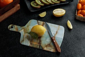 Vue latérale du citron avec un couteau sur une planche à découper avec des tranches de kiwi tranche de citron vert citron coupé et des kumquats entiers sur fond noir