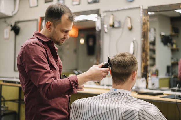 Vue latérale du coiffeur donnant une coupe de cheveux