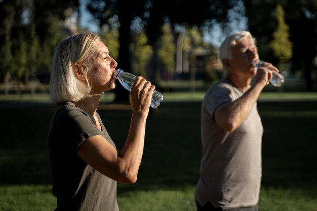 Vue latérale du couple d'âge mûr de l'eau potable à l'extérieur