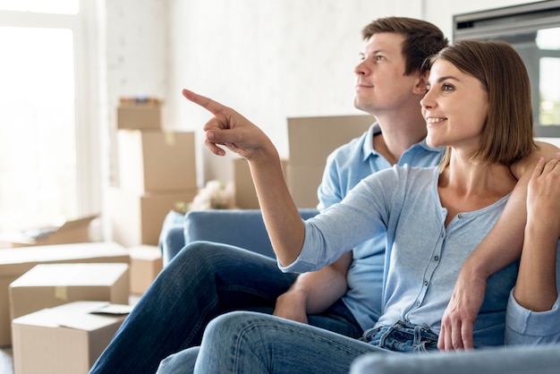 Vue latérale du couple sur le canapé en montrant quelque chose en sortant