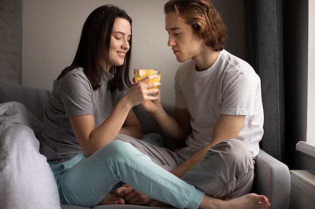 Photo gratuite vue latérale du couple sur le canapé partageant un verre de jus d'orange