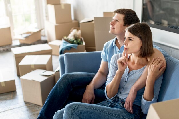 Vue latérale du couple sur le canapé prépare les choses à déménager