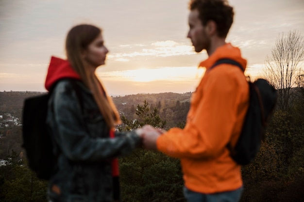 Photo gratuite vue latérale du couple main dans la main au coucher du soleil sur un road trip