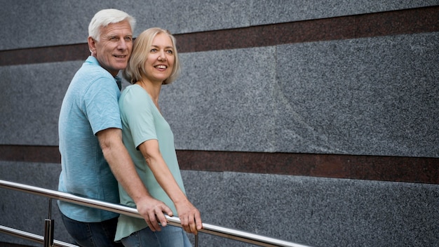 Vue latérale du couple de personnes âgées posant ensemble à l'extérieur