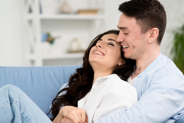 Vue latérale du couple romantique sur le canapé à la maison