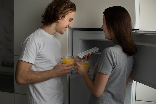 Photo gratuite vue latérale du couple souriant tenant des verres de jus d'orange