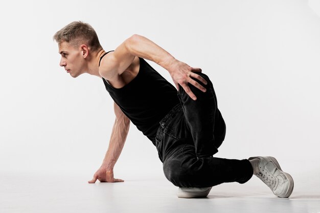 Vue latérale du danseur en jeans et baskets posant en dansant