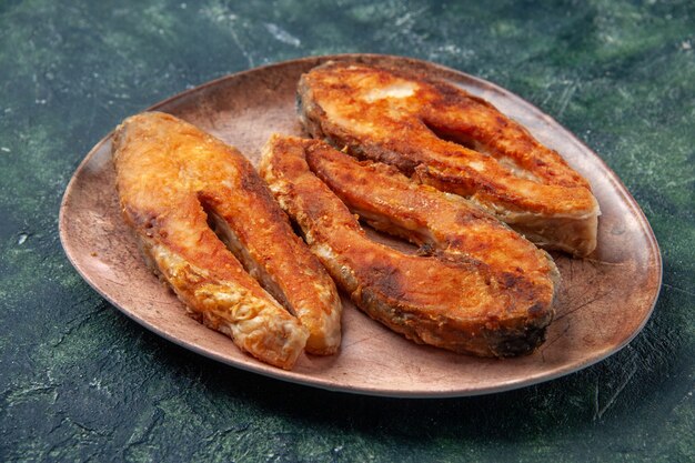 Vue latérale du délicieux poisson frit sur une plaque brune sur le côté gauche sur le tableau des couleurs de mélange avec de l'espace libre