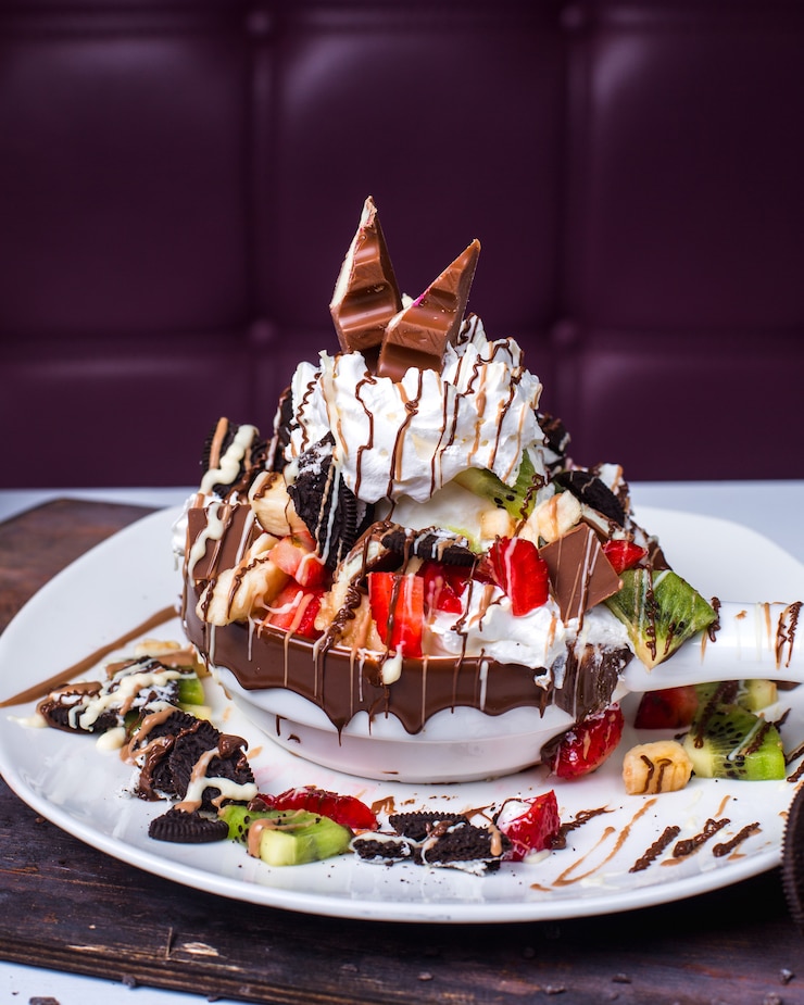 Photo gratuit vue latérale du dessert aux fruits en couches avec crème fouettée et sirop de chocolat sur une plaque
