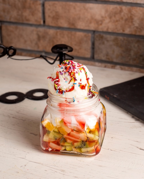 Vue latérale du dessert à la crème glacée aux fruits dans un bocal en verre