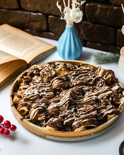 Vue latérale du dessert avec des rouleaux de pâte recouverts de sirop de chocolat sur la table