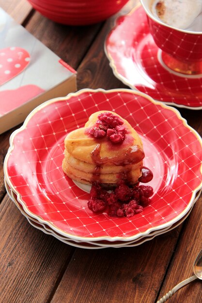 Vue latérale du foie en forme de coeur avec des framboises et une tasse de café