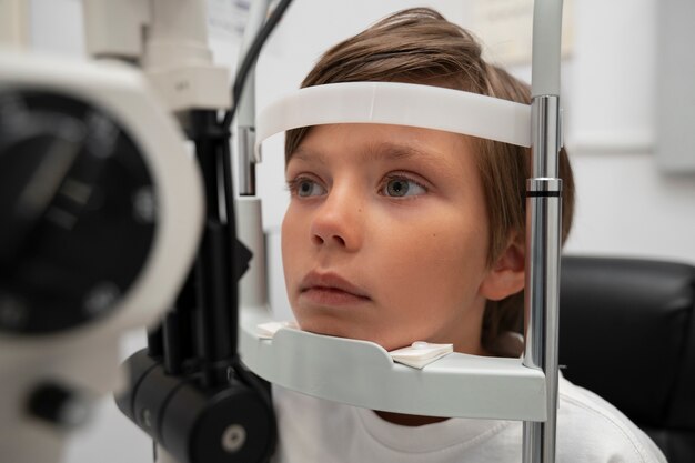 Vue latérale du garçon à l'examen oculaire