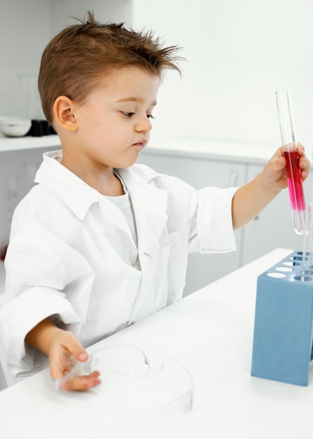 Photo gratuite vue latérale du garçon scientifique dans le laboratoire avec des tubes à essai