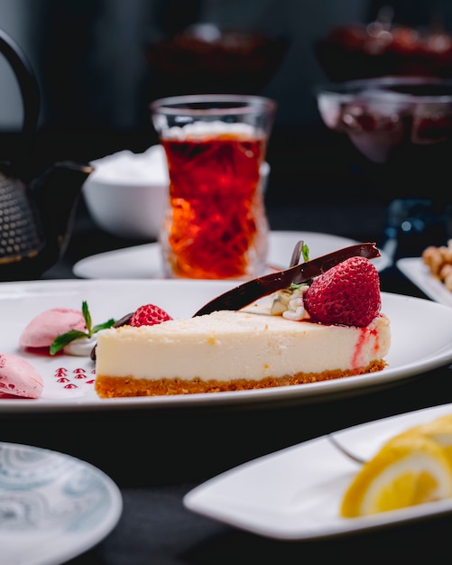 Photo gratuite vue latérale du gâteau au fromage décoré de fraises fraîches sur une plaque blanche