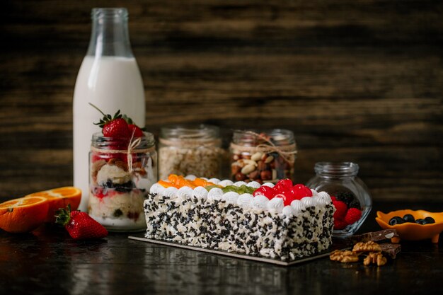 Vue latérale du gâteau aux fruits avec de la crème fouettée sur une surface rustique