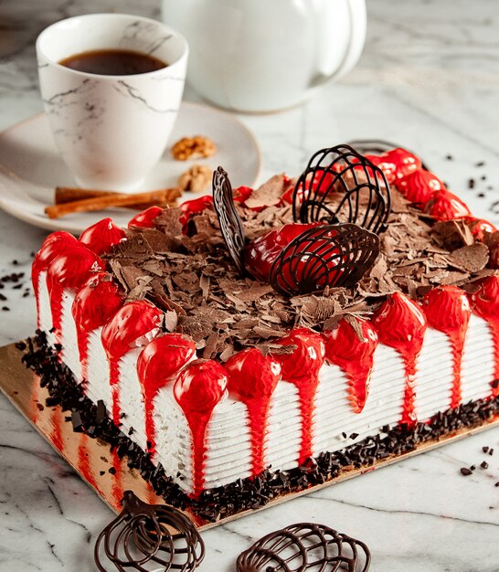 Vue latérale du gâteau aux fruits garni de flocons de chocolat sur la table servi avec du thé