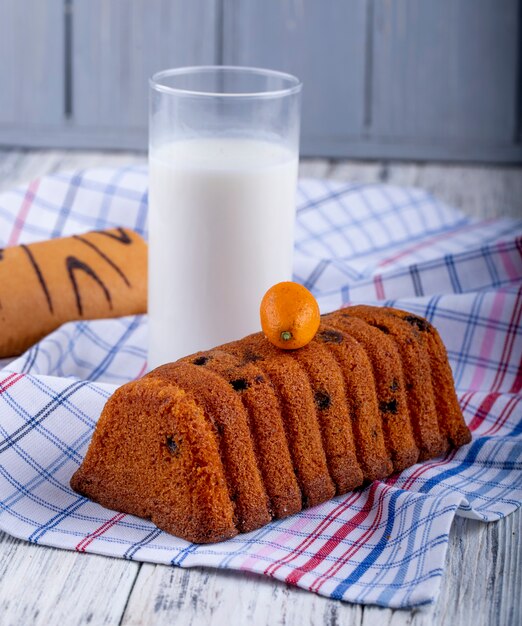 Vue latérale du gâteau aux raisins secs et un verre de lait sur une nappe