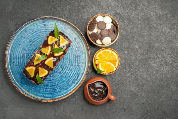 Vue latérale du gâteau moelleux décoré de citron et de chocolat sur table noire