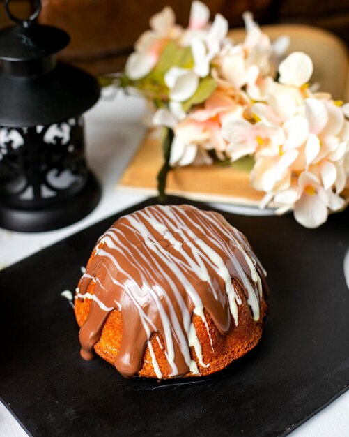 Vue latérale du gâteau à la sauce au chocolat sur une planche de bois