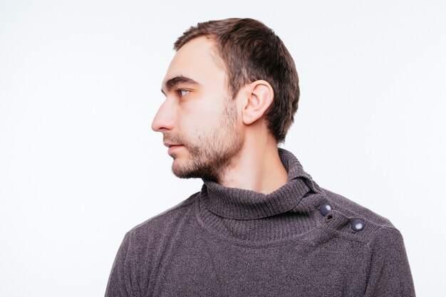 Vue latérale du jeune homme barbu isolé sur mur gris