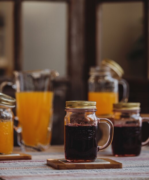 Vue latérale du jus de cerise frais dans un bocal en verre sur un petit support en bois