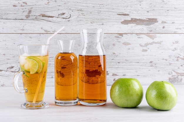 Vue latérale du jus de pomme sur une table en bois blanc