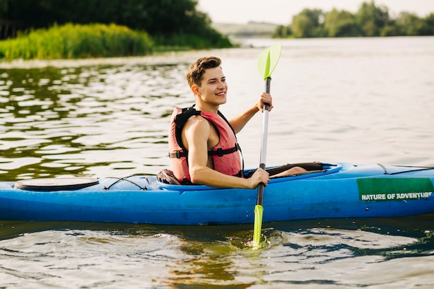 Vue latérale du kayakiste mâle kayak sur le lac