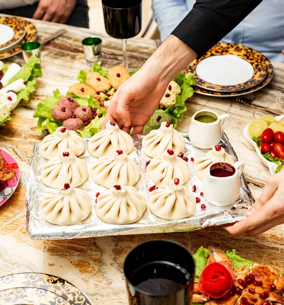 Vue latérale du khinkali géorgien traditionnel servi avec des sauces épicées et des sauces sur un plateau