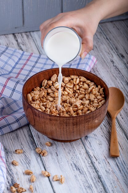 Vue latérale du lait versant sur du riz sucré soufflé rustique