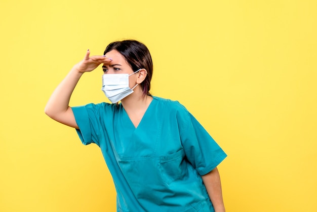 Vue latérale du médecin dans un masque regarde ailleurs