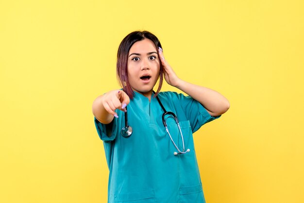 Vue latérale du médecin en uniforme médical bleu pointe vers l'avant