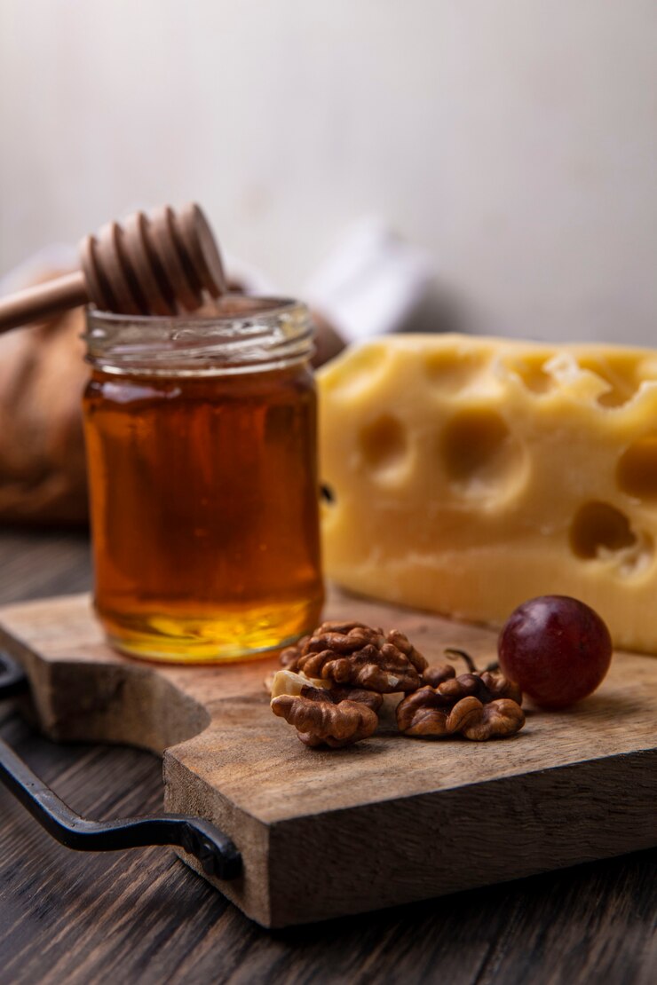 Photo gratuit vue latérale du miel dans un pot avec du fromage et des noix sur un support
