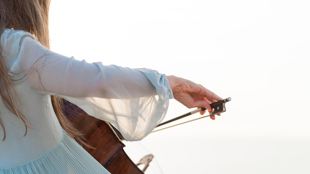 Vue latérale du musicien féminin jouant du violoncelle avec copie espace