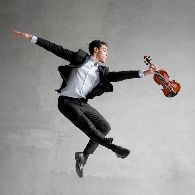 Photo gratuite vue latérale du musicien posant en l'air tout en tenant le violon
