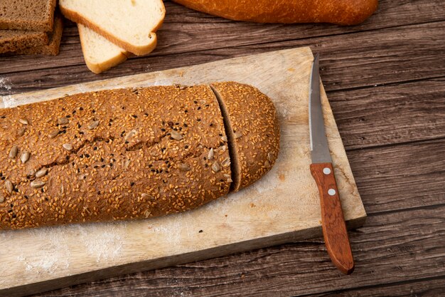 Vue latérale du pain sandwich coupé et couteau sur une planche à découper sur fond de bois