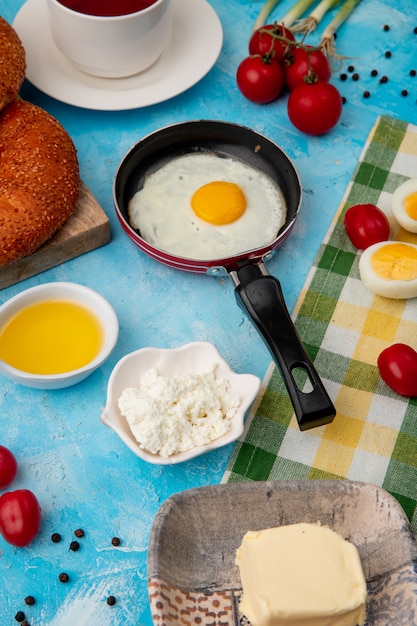 Vue latérale du petit déjeuner avec du beurre d'oeuf frit fromage cottage cottage sur fond bleu