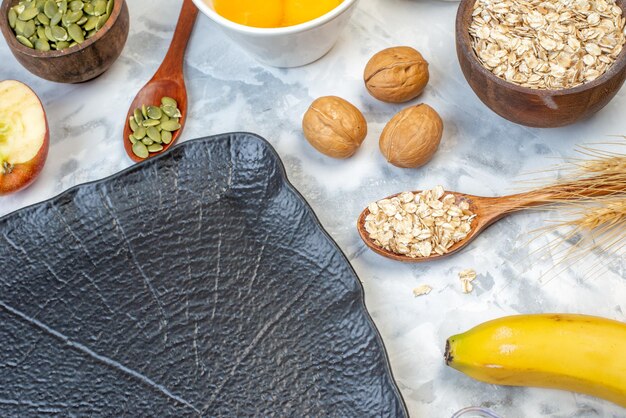 Vue latérale du plateau noir et des pommes fraîches cuillère aux noix de confiture d'oeufs fêlés sur une surface en marbre